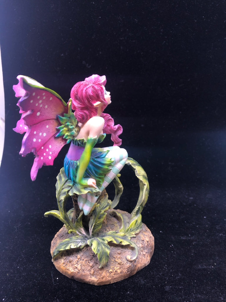 RESIN FAIRY SITTING ON A STUMP W/ PURPLE WINGS.