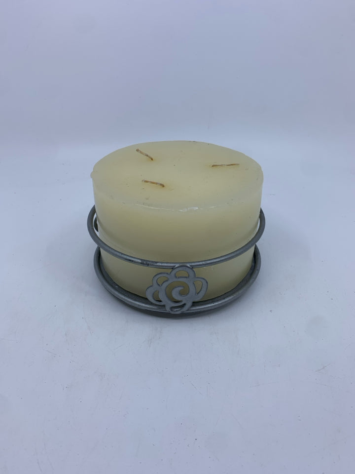 LARGE CANDLE IN METAL HOLDER.