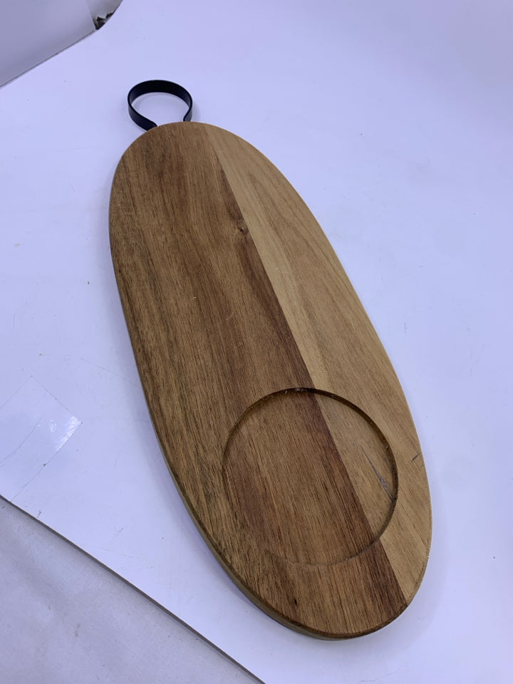 OVAL WOOD CUTTING BOARD WITH BLACK METAL HANDLE.