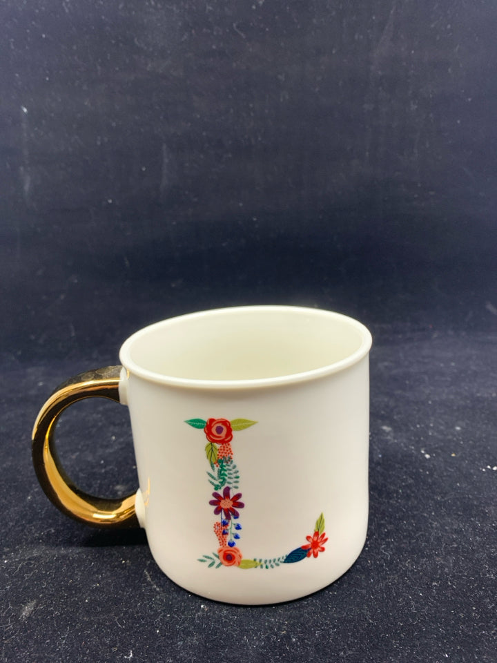 WHITE MUG W/ FLORAL "L" GOLD HANDLE.