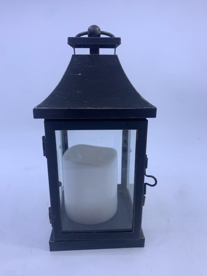 BLACK DISTRESSED LANTERN WITH ELECTRIC WHITE CANDLE.