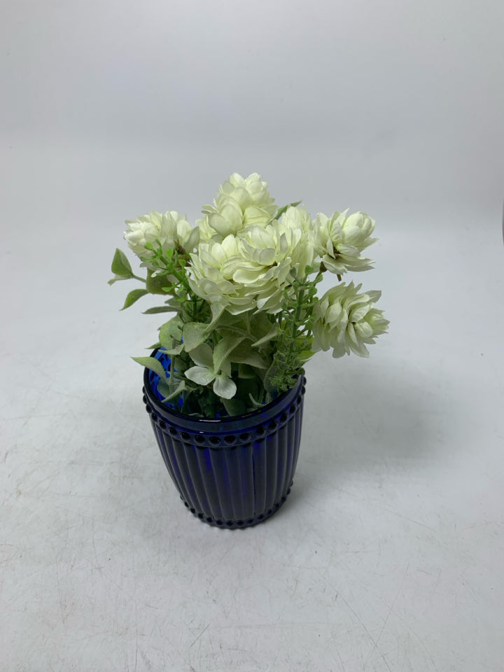 DARK BLUE GLASS VASE W/ SMALL WHITE FLOWERS.