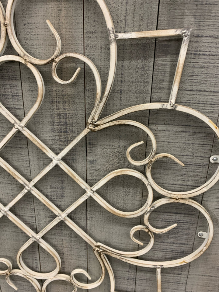 WHITE METAL MEDALLION ON GREY WOOD WALL DECOR.