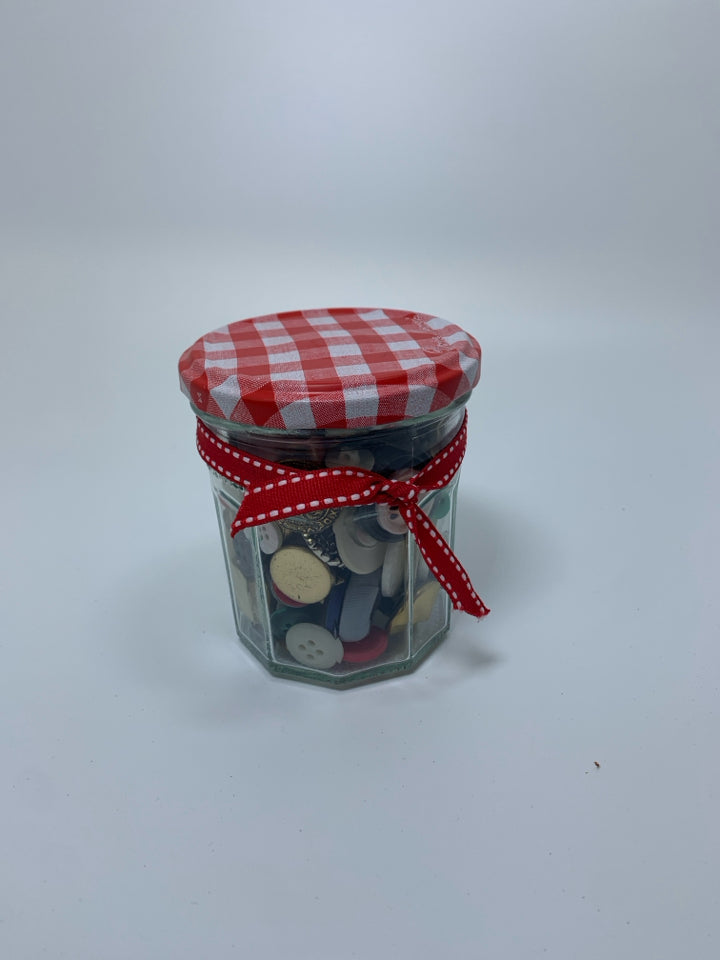 GLASS JAR FULL OF ASSORTED BUTTONS.