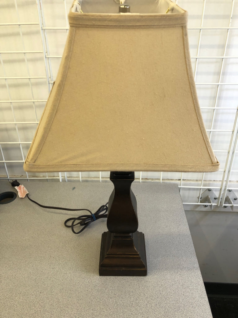 DARK WOOD BASE LAMP W/TAN FABRIC SHADE.