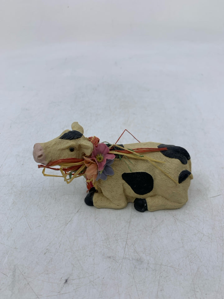 LAYING DOWN COW W/ STRAW AROUND NECK.