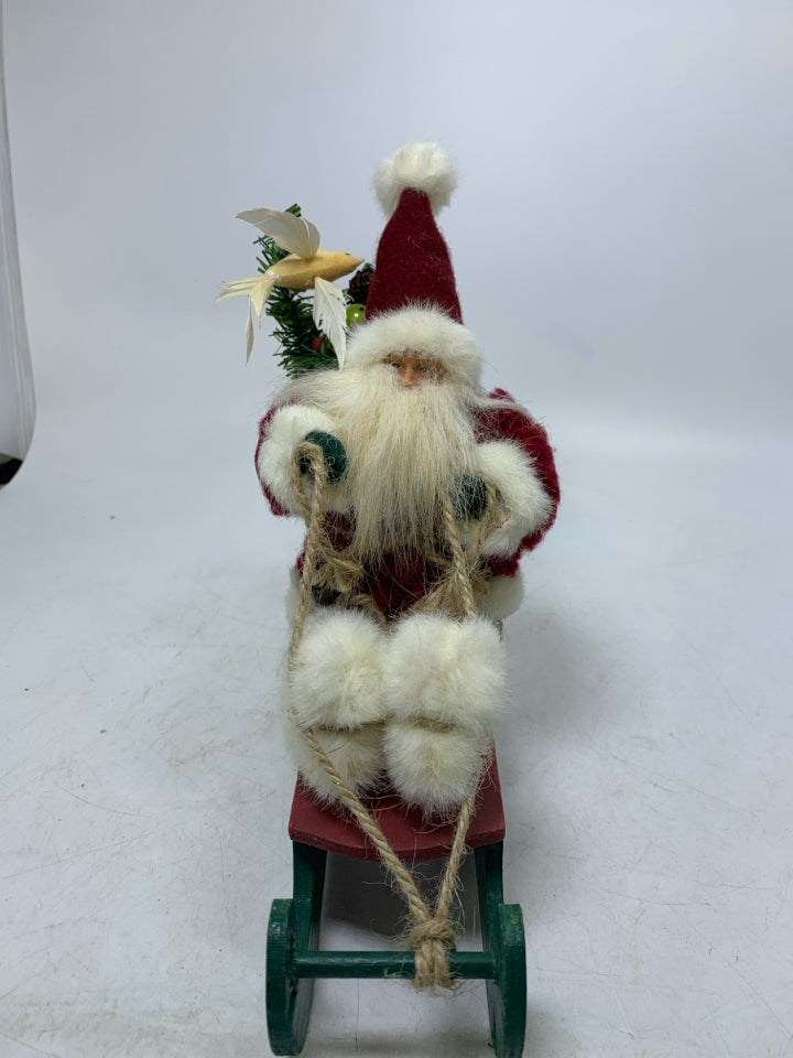 SMALL PLUSH SANTA ON GREEN SLED.