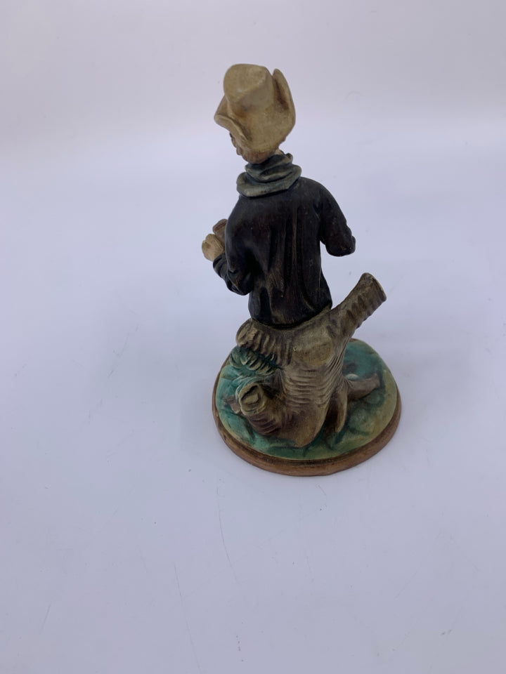 MAN PLAYING ACCORDION LEANING ON TREE.