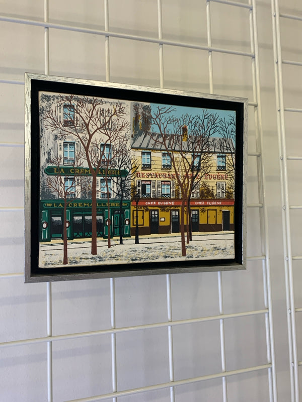 STREET SCENE CANVAS -SIGNED IN SILVER FRAME.