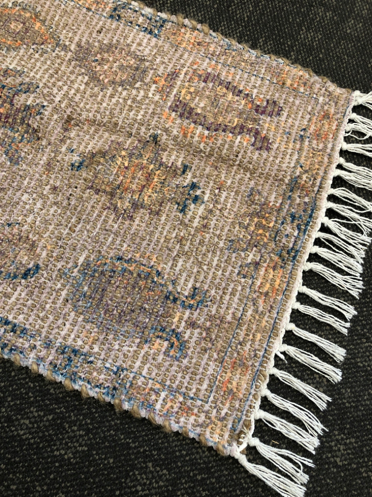SMALL MULTI-COLORED WOVEN RUG W/ FRINGE ON ENDS.