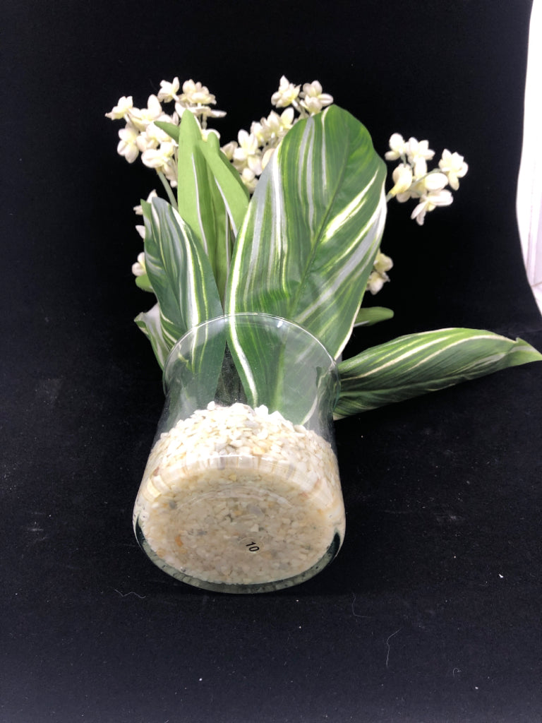 FAUX LEAVES W/ WHITE FLOWERS IN CLEAR VASE W/ WHITE ROCKS.