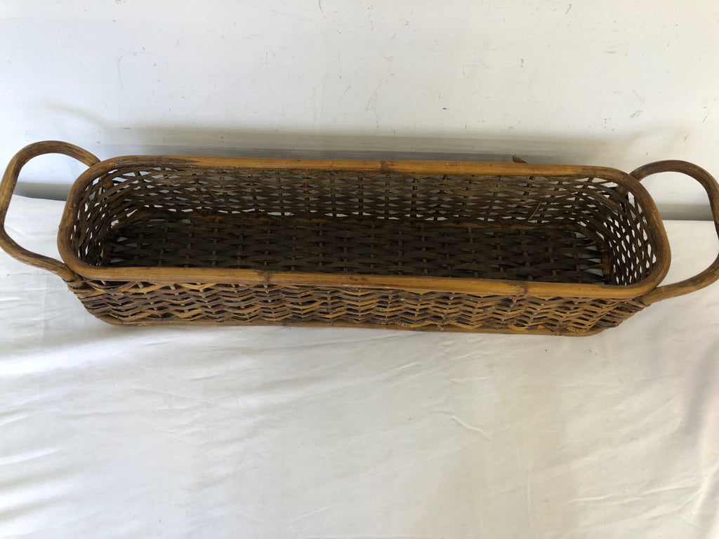 LONG WOVEN WICKER BASKET W/ DOUBLE HANDLES.