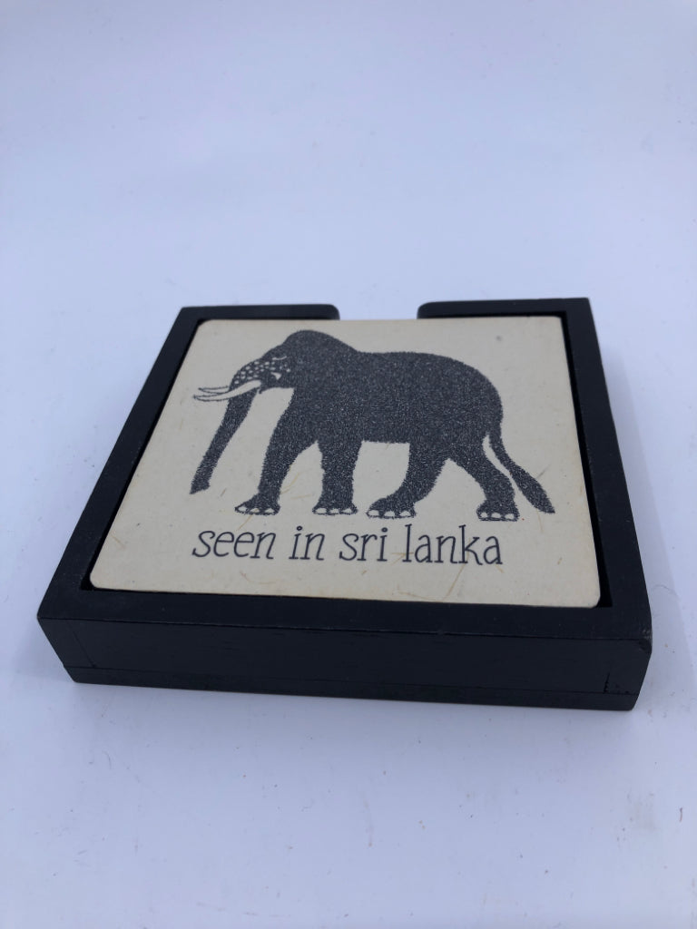 4 ELEPHANT COASTERS IN BLACK HOLDER.