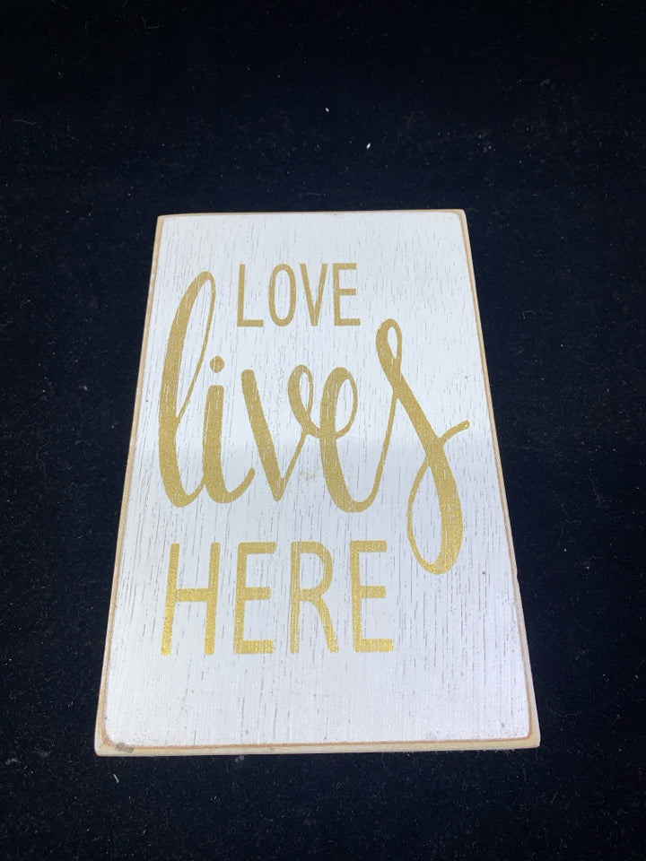 LOVE LIVES HERE WHITE AND GOLD SIGN.