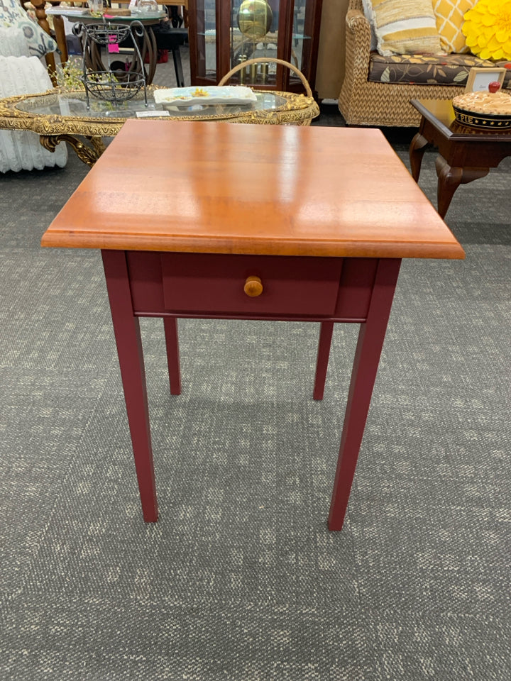 CHERRY WOOD SIDE TABLE W/DRAWER AND RED PAINTED LEGS.