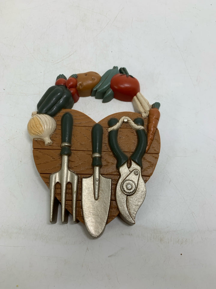 SMALL VTG PLASTIC HEART SHAPED PLAQUE W/ VEGGIES & GARDEN TOOLS.