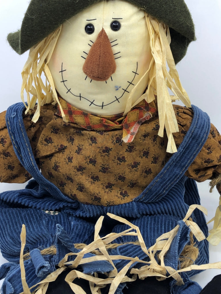 SHELF SITTING SCARECROW IN OVERALLS.