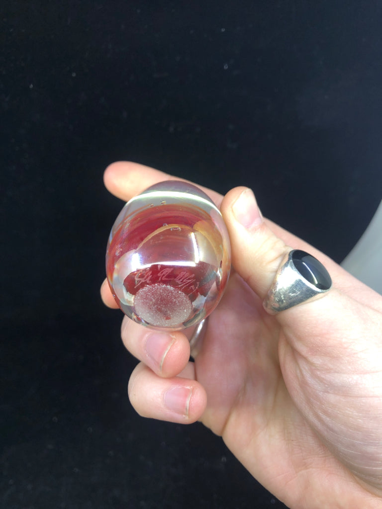 EGG SHAPED GLASS PAPER WEIGHT W/ RED SWIRL IRIDESCENT COLOR.