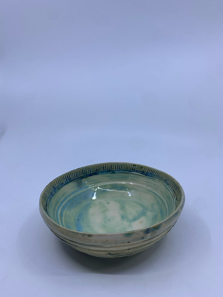 LIGHT GREEN POTTERY BOWL W/ SOME BLUE LINED EDGE.