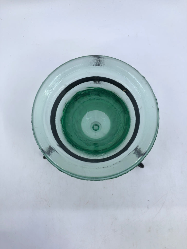 THICK GREEN GLASS TEA LIGHT HOLDER IN BLACK FOOTED STAND.