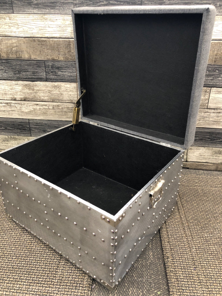 SMALL GREY STUDDED OTTOMAN W METAL HANDLES AND STORAGE.