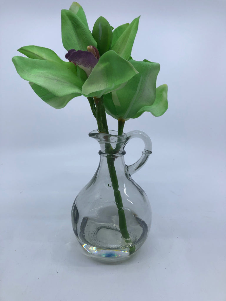 GLASS PITCHER VASE W/GREENS AND PURPLE FLOWERS.