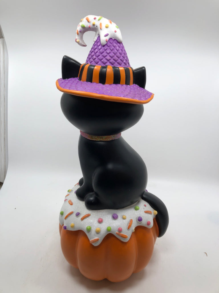BLACK CAT W/ CANDY HAT SITTING ON LIGHT UP JACKO LANTERN.