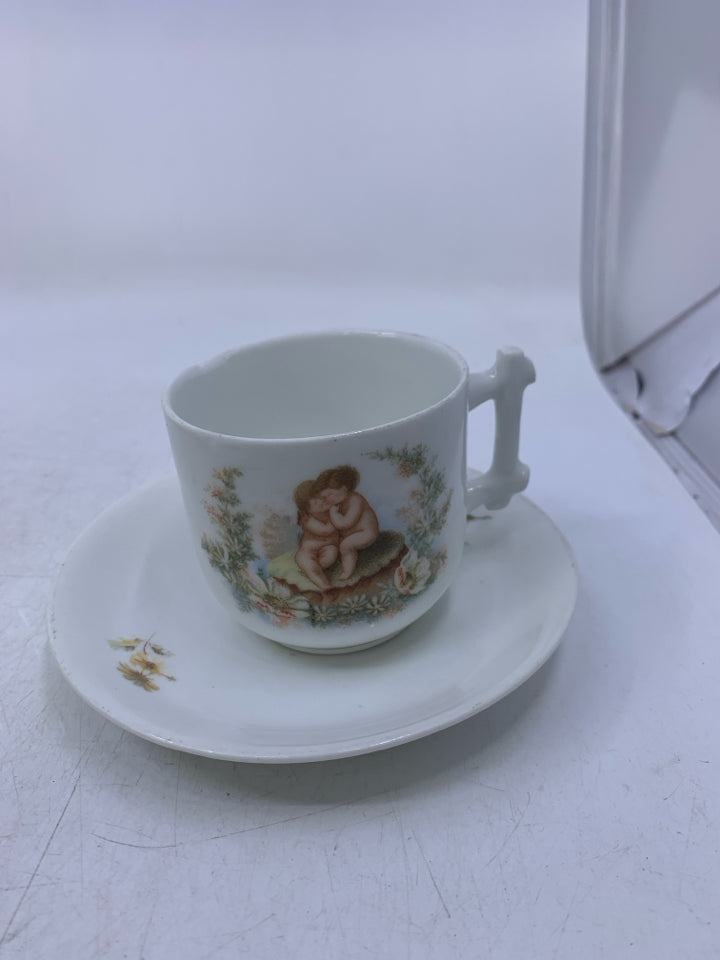 WHITE TEA CUP W/ 2 CHERUBS SITTING ON ROCK TEA CUP SAUCER.