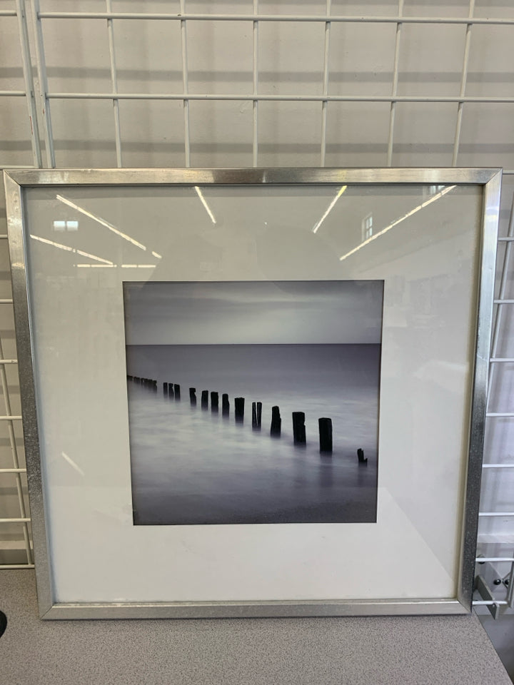 FOGGY BEACH W/WOOD PILLARS IN SILVER FRAME.