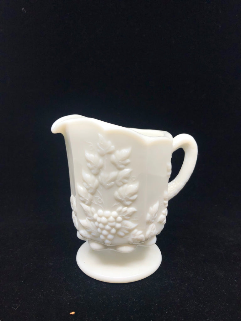 VTG MILK GLASS FOOTED PITCHER W/ EMBOSSED GRAPES + VINES.