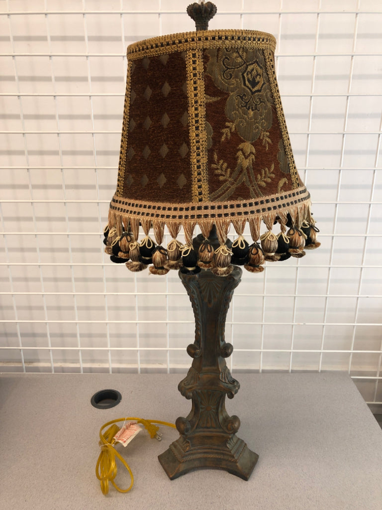 HEAVY LAMP W/SCROLL DISTRESSED BASE AND FABRIC SHADE W/TASSELS.