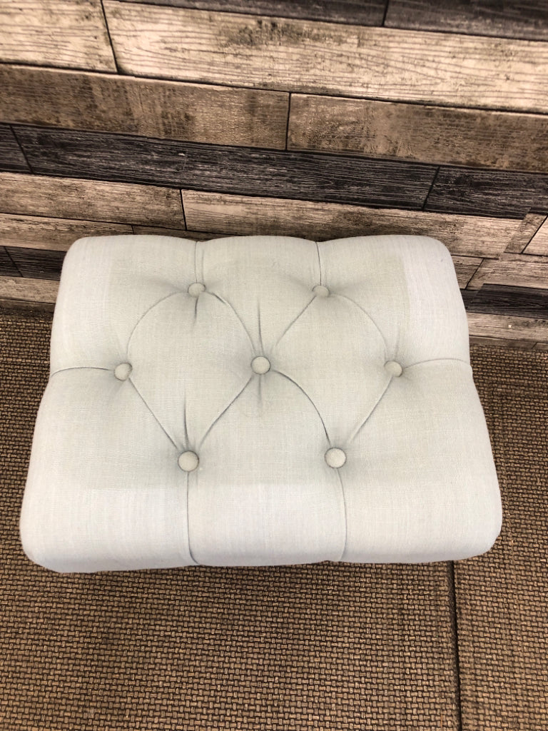 LIGHT BLUE BUTTON DETAIL OTTOMAN W/ BLACK LEGS.