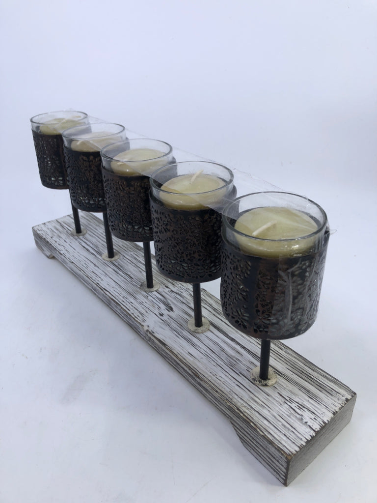 5 METAL CANDLE HOLDERS ON DISTRESSED WOOD BLOCK.