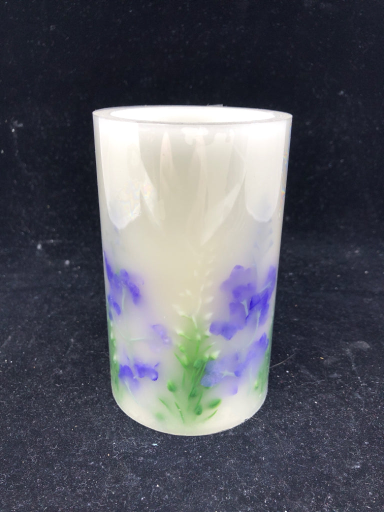 FAUX BATTERY PILLAR CANDLE W/ PURPLE FLOWERS.