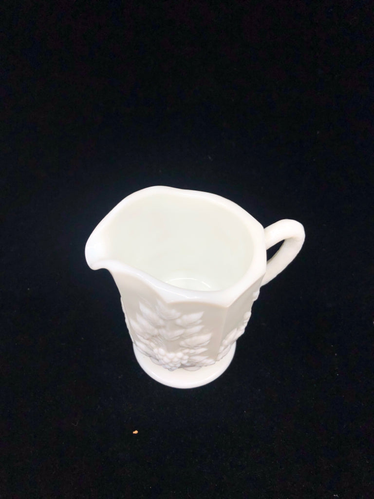 VTG MILK GLASS FOOTED PITCHER W/ EMBOSSED GRAPES + VINES.