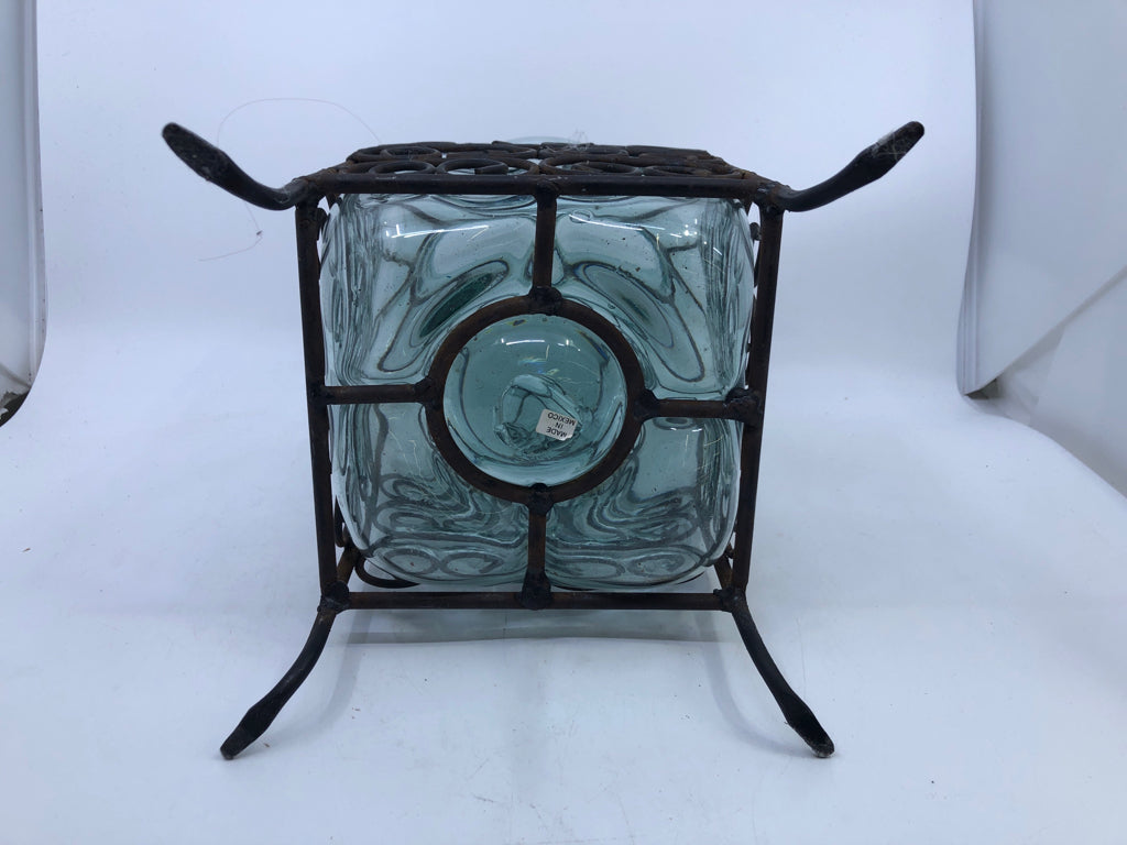 THICK GLASS VASE ENCASED IN SCROLL METAL FOOTED CAGE.