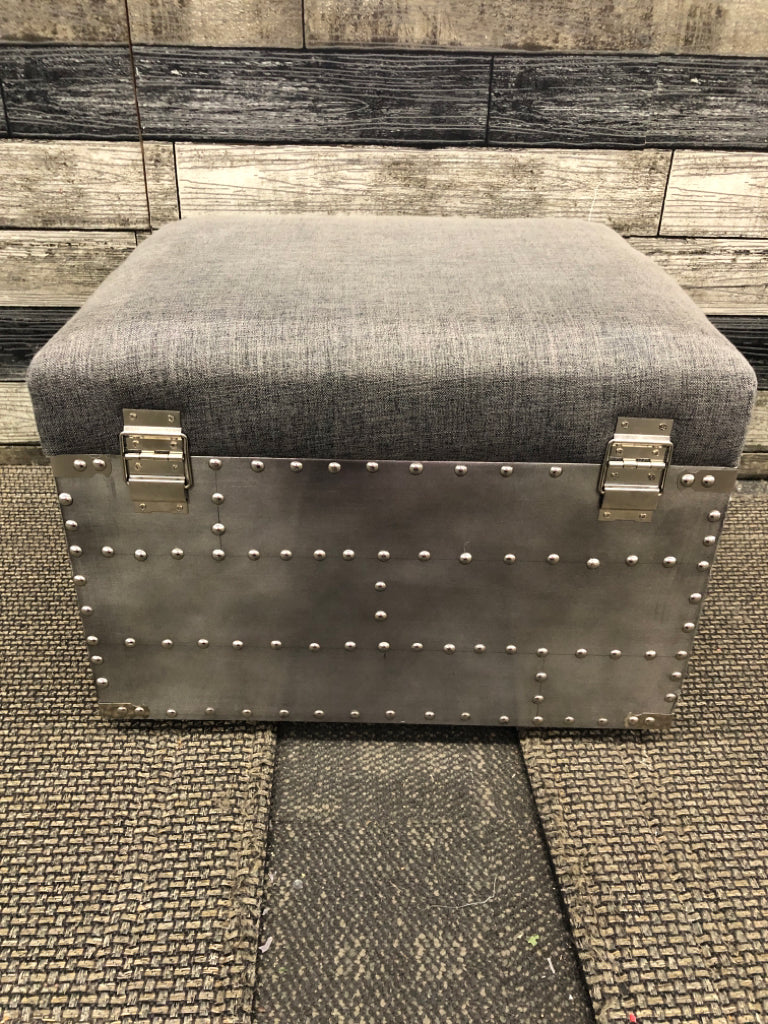 SMALL GREY STUDDED OTTOMAN W METAL HANDLES AND STORAGE.