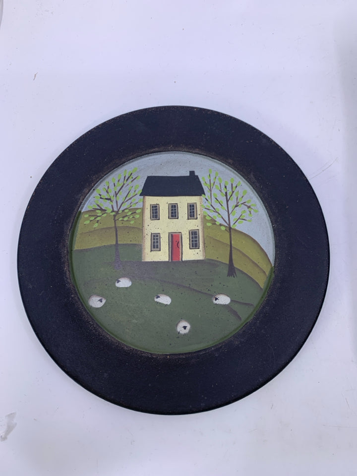 BLACK DECORATIVE PLATE W/ WHITE HOUSE SHEEP IN FRONT YARD.