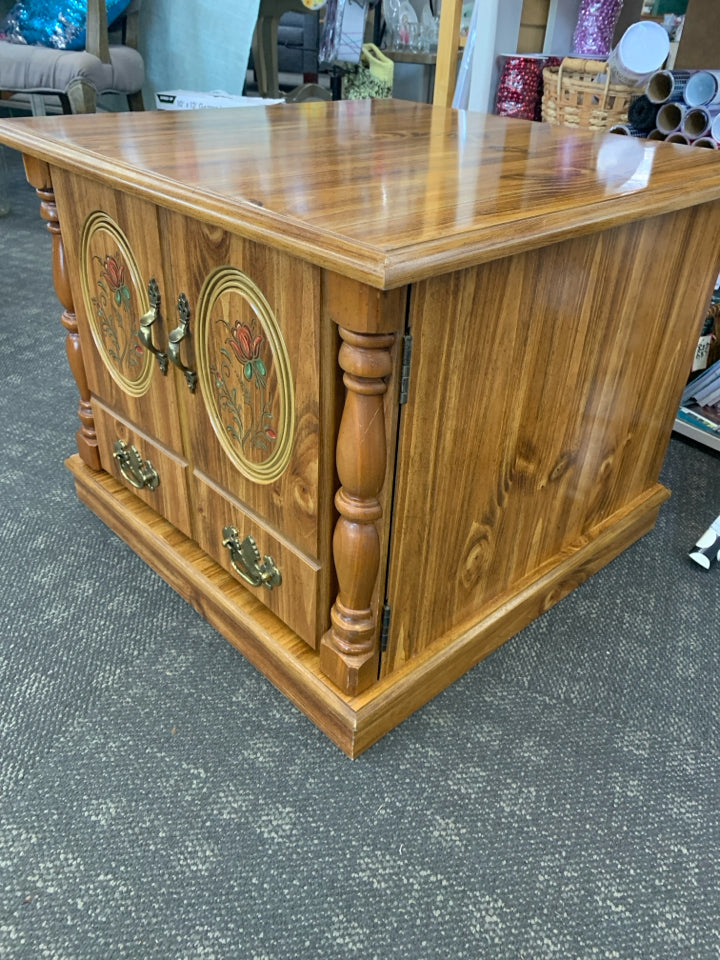 SHORT FAUX WOOD TABLE W/ CABINET RED ROSE DETAIL ON DOORS.