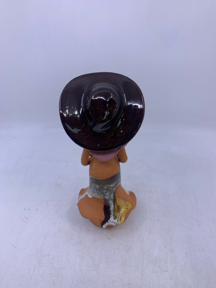 CLAY FACELESS WOMAN BROWN HAT HOLDING PINK FLOWERS.