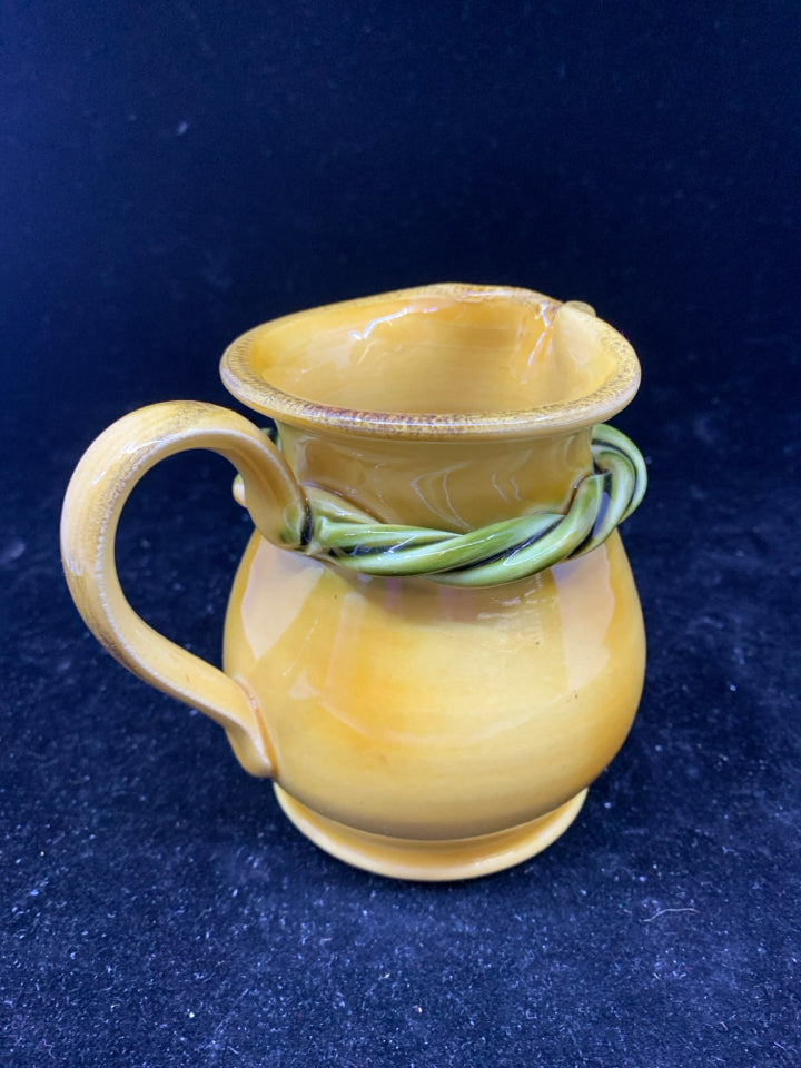YELLOW POTTERY CREAMER W/ GREEN ROPE DETAIL.