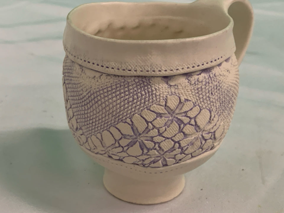 HANDMADE POTTERY EMBOSSED TEACUP AND SAUCER.