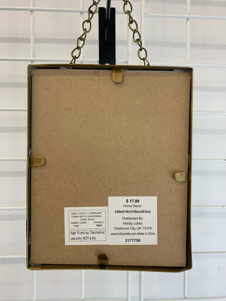 WHITE FLORAL PRINT IN HANGING BRASS FRAME.