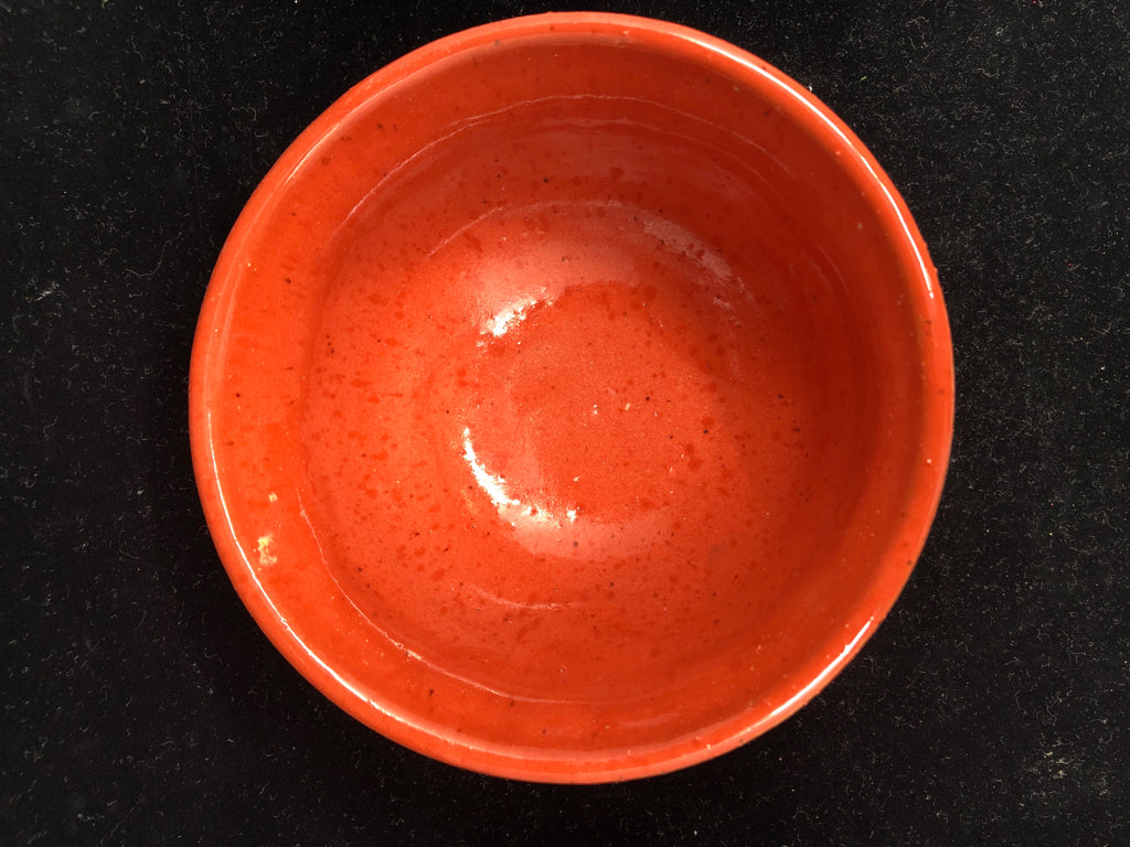 ORANGE POTTERY BOWL W LIGHT OUTSIDE.