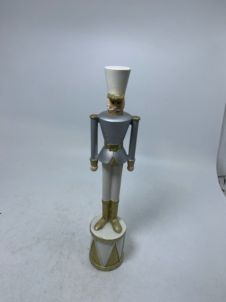 SILVER/GOLD RESIN NUTCRACKER STANDING ON DRUM.