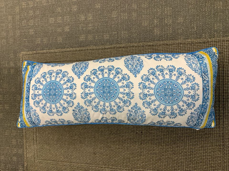 LONG BLUE FLORAL PILLOW W/YELLOW ACCENTS.