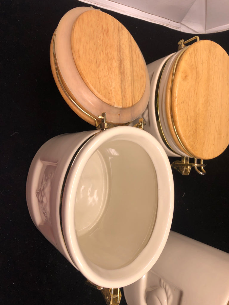 3 OVAL CREAM CERAMIC CANISTERS W/ WOOD TOPS EMBOSSED FRUITS.