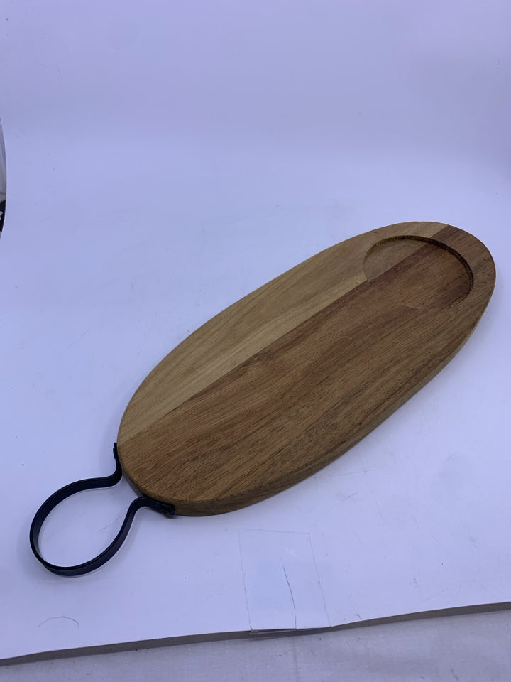 OVAL WOOD CUTTING BOARD WITH BLACK METAL HANDLE.