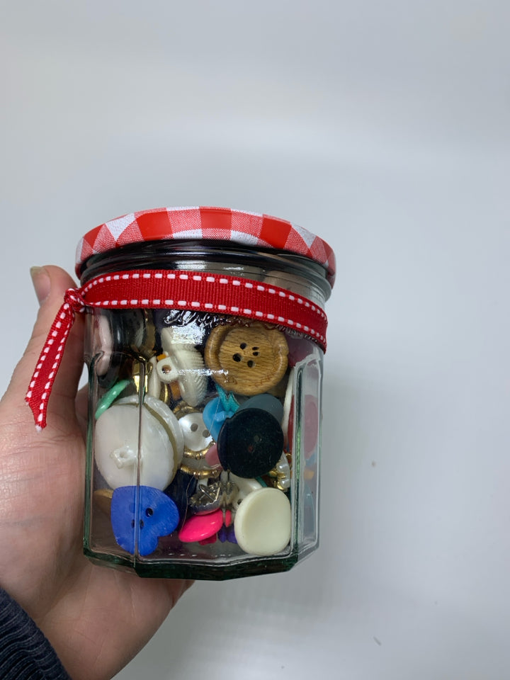 GLASS JAR FULL OF ASSORTED BUTTONS.