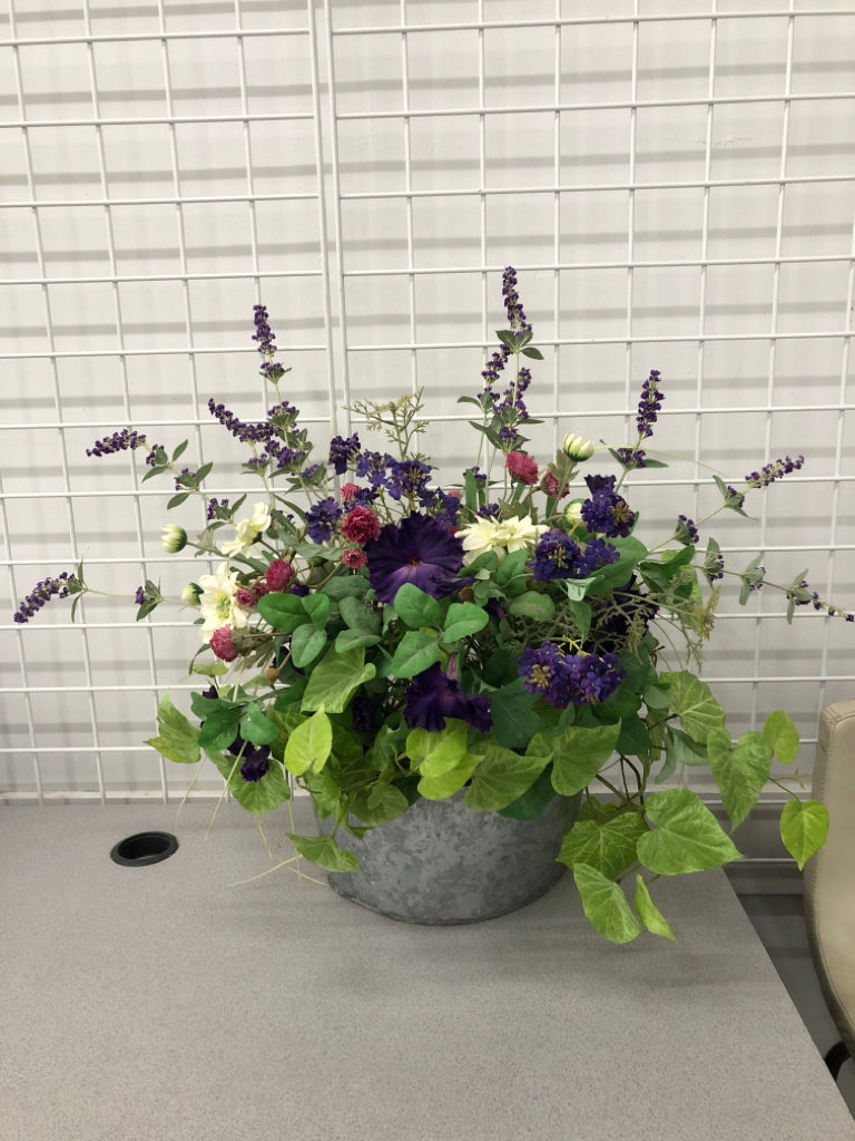 FAUX PURPLE FLOWERS IN GALVANIZED TIN WALL POCKET.